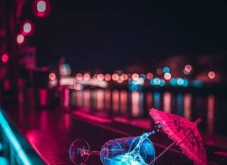 Lyon Night Bars vs Paris: Which City Wins on Drinks? Neon-lit bar, spilled drink, oversized umbrella, blurred river background.