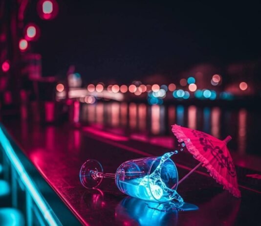 Lyon Night Bars vs Paris: Which City Wins on Drinks? Neon-lit bar, spilled drink, oversized umbrella, blurred river background.