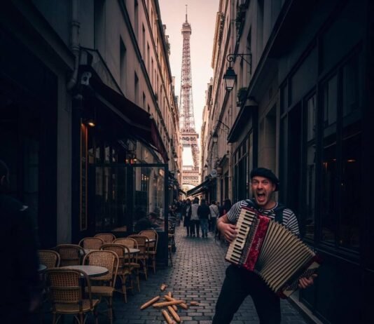 Safe Paris Areas Near Eiffel Tower & Top Attractions Eiffel Tower through alley, accordion player, café chairs.