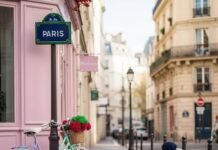 The Safest Paris Neighborhoods for First-Time Visitors Paris street with bike, artist, and pastel cafe.