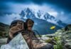 The Most Scenic Alps Hiking Trails Near Chamonix Muddy hiking boot, map, and wildflower with Mont Blanc under stormy sky.